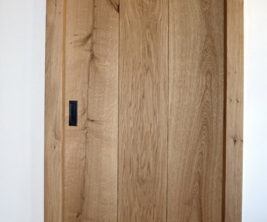 Posuvné dveře do pouzdra jednokřídlé fošnové v obložkové zárubni. Dubové dřevo, drásané, nástřik lakem s natur efektem.
