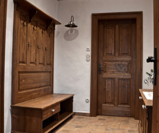 Věšáková stěna s botníkem a kazetové jednokřídlé dveře s obložkovou zárubní, vše smrkové dřevo, drásané, nátěr lazurou.