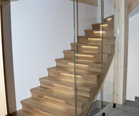 Sedlový obklad betonových schodů se skleněným zábradlím a podsvícením LED pásky z dubového dřeva.