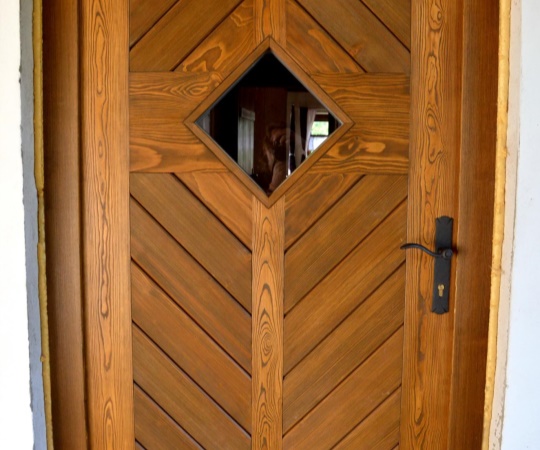 Dveře vstupní jednokřídlé, prkenné s okénkem, v rámové zárubni, smrk, drásané, nátěr olejovou lazurou OSMO.