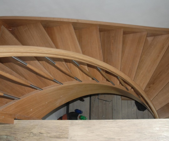 Samonosné dubové schodiště ve tvaru "U" s obloukovým madlem a schodnicí, nástřik transparentní lak.