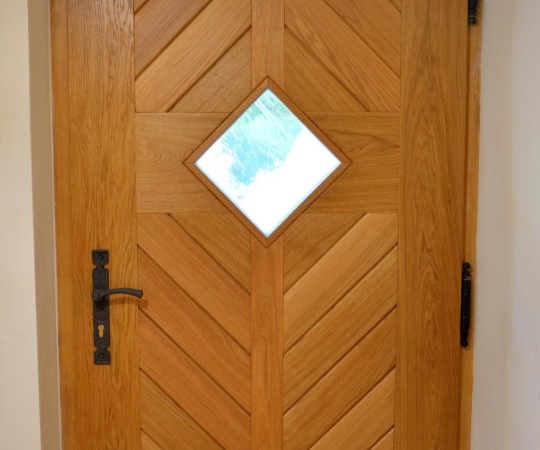 Dveře vstupní jednokřídlé v rámové zárubni s nadsvětlíkem, prkenné s okénkem, dub, drásané, nátěr olejem OSMO.