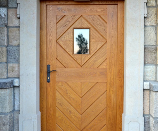 Dveře vstupní jednokřídlé, prkenné s okénkem, v rámové zárubni do pískovce, dub, drásané, nátěr lazurou.