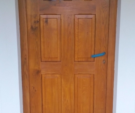 Vstupní dveře, kazetové, částečně prosklené, jednokřídlé v rámové zárubni . Dubové dřevo, drásané, nátěr lazurou.