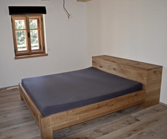 Manželská postel s peřiňákem v moderním hladkém stylu z dubového dřeva.