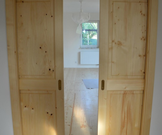 Dveře dvoukřídlé vnitřní kazetové, posuvné do stavebního pouzdra v obložkové zárubni, smrkové dřevo,nátěr olejem.
