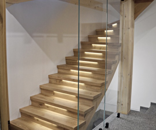 Sedlový obklad betonových schodů se skleněným zábradlím a podsvícením LED pásky z dubového dřeva, drásané, nástřik lakem s natur efektem.