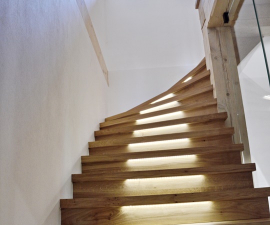 Sedlový obklad betonových schodů se skleněným zábradlím a podsvícením LED pásky z dubového dřeva.