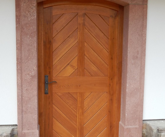 Dveře vstupní jednokřídlé, palubkové, v rámové zárubni do pískovce, dub, nátěr lazurou.