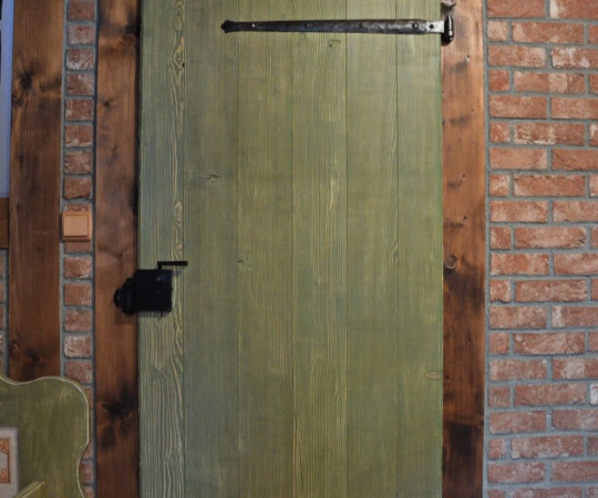 Dveře vnitřní fošnové v trámové zárubni, smrkové dřevo, drásané, nátěr lazurou olivově zelenou lazurou.