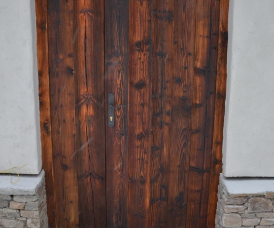 Dveře vstupní dvoukřídlé, prkenné, v rámové zárubni, ze starého, sluncem a větrem ošlehaného dřeva, nátěr OSMO bezbarvý olej.
