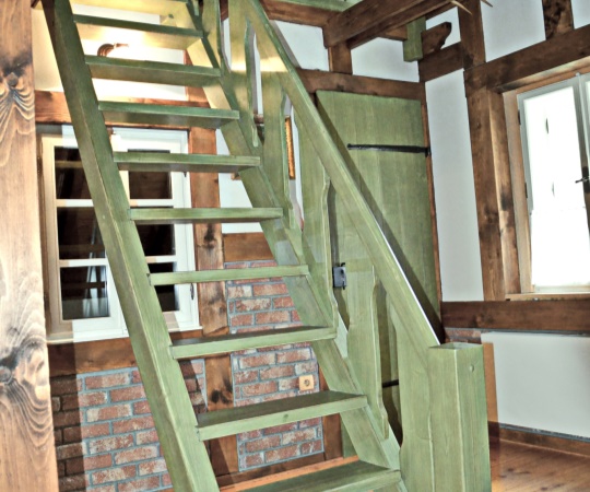 Samonosné schody přímé na hambalka, včetně zábradlí a galerie, fošnové dveře s kovanými závěsy. Smrkové dřevo drásané, nátěr zelenou lazurou.