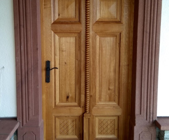 Dveře vstupní kazetové, rámová zárubeň v kamenném ostění, replika historických dveří, dubové dřevo, nátěr lazurou. 