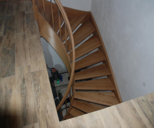Samonosné dubové schodiště ve tvaru "U" s obloukovým madlem a schodnicí, nástřik transparentní lak.