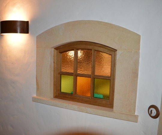 Interiérové okénko v pískovcovém ostění, dubové dřevo, drásané, chemicky zbarvené, nátěr olejem, barevné sklo.