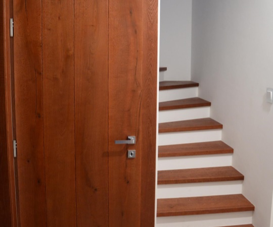 Obklad schodů sladěný s dveřmi, dubové dřevo, drásané, mořené, nástřik supermatným lakem.