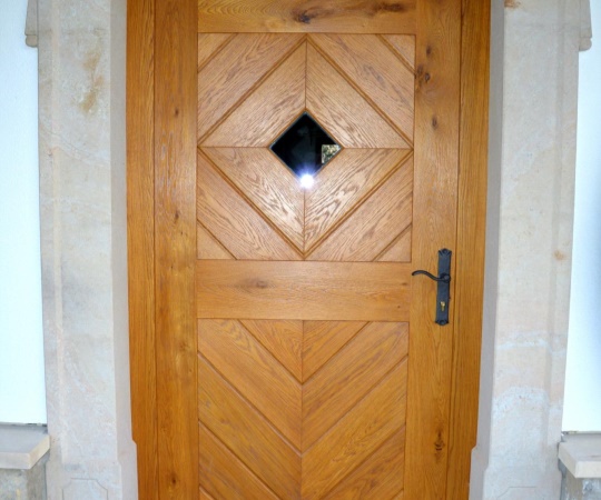 Dveře vstupní jednokřídlé, prkenné s okénkem, v rámové zárubni do pískovce, dub, drásané, nátěr lazurou. 