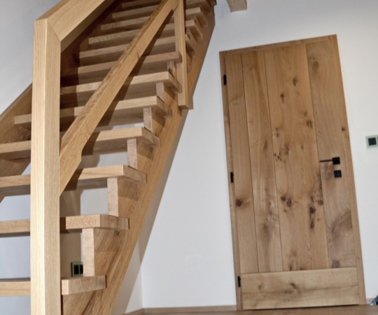 Polosedlové samonosné schody na hambalka, včetně zábradlí a fošnové vnitřní dveře v obložkové zárubni, vše z dubového dřeva.